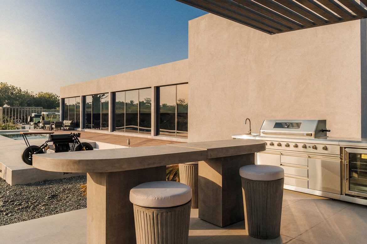 The concrete outdoor kitchen bar with stools and a grill