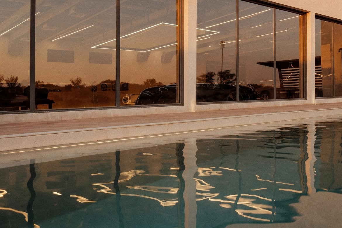 The glass facade mirrored in still pool water in the late afternoon
