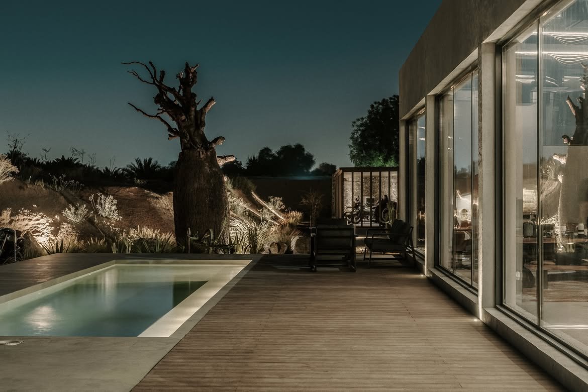 The pool and the baobab at night with the house glowing behind