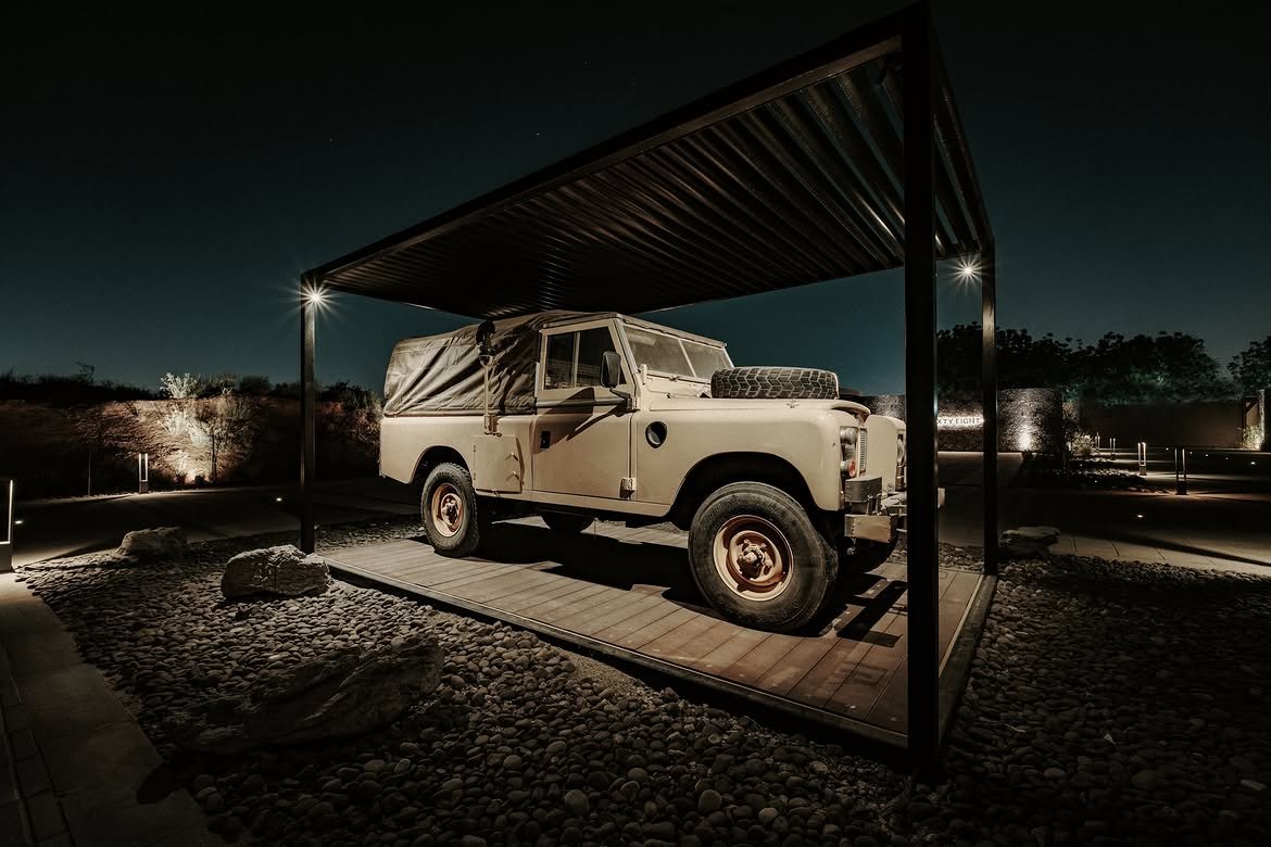 A Land Rover parked and lit under the pergola at night