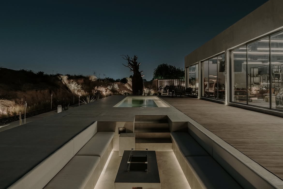 The same pool deck after dark, the sunken fire pit lit