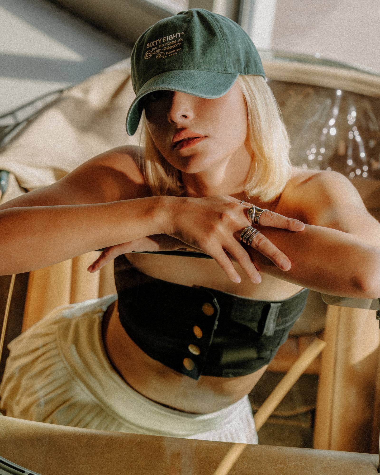 Close portrait in a dark green cap, brim low over the eyes, warm golden light inside a car.